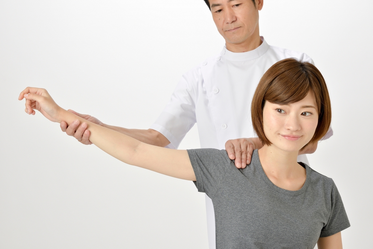 右肩甲骨の痛みの原因を確認するため、整体で肩と腕の可動域をチェックしている様子