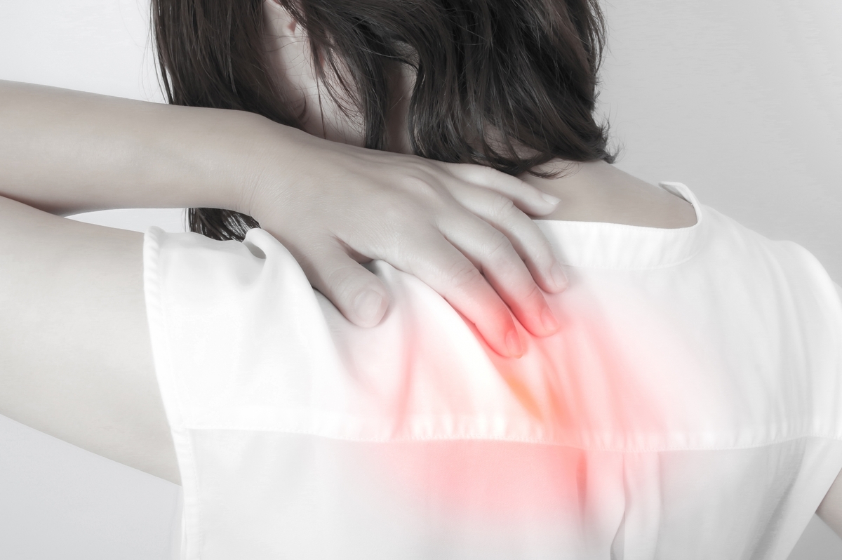 肩甲骨の間が痛い女性が背中を押さえてつらさを感じているイメージ