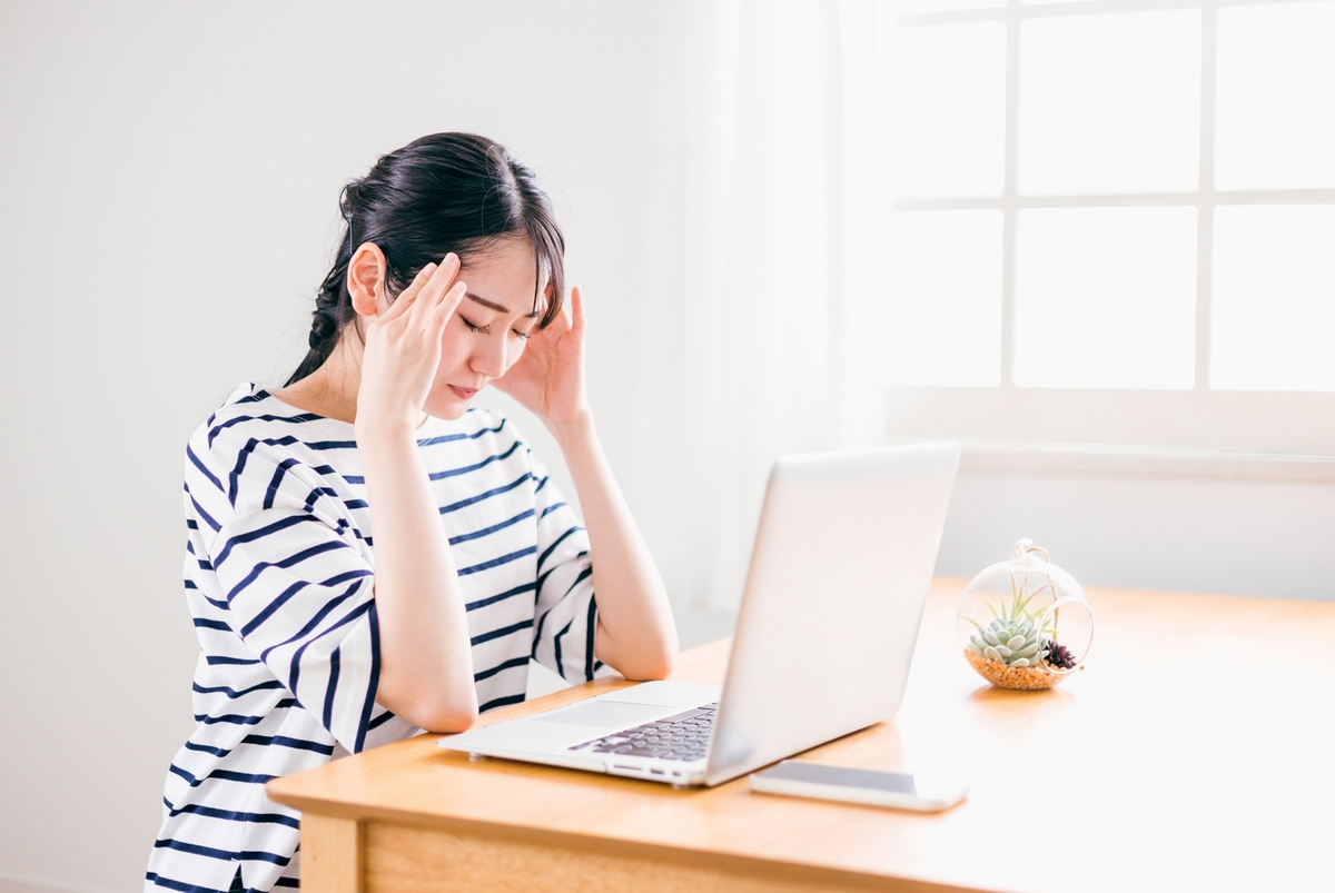頭痛で頭をおさえる女性