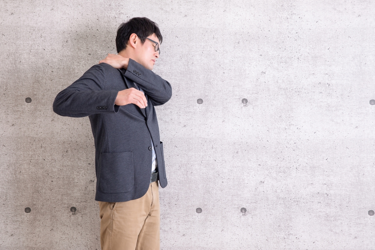 右肩の痛みを押さえる男性